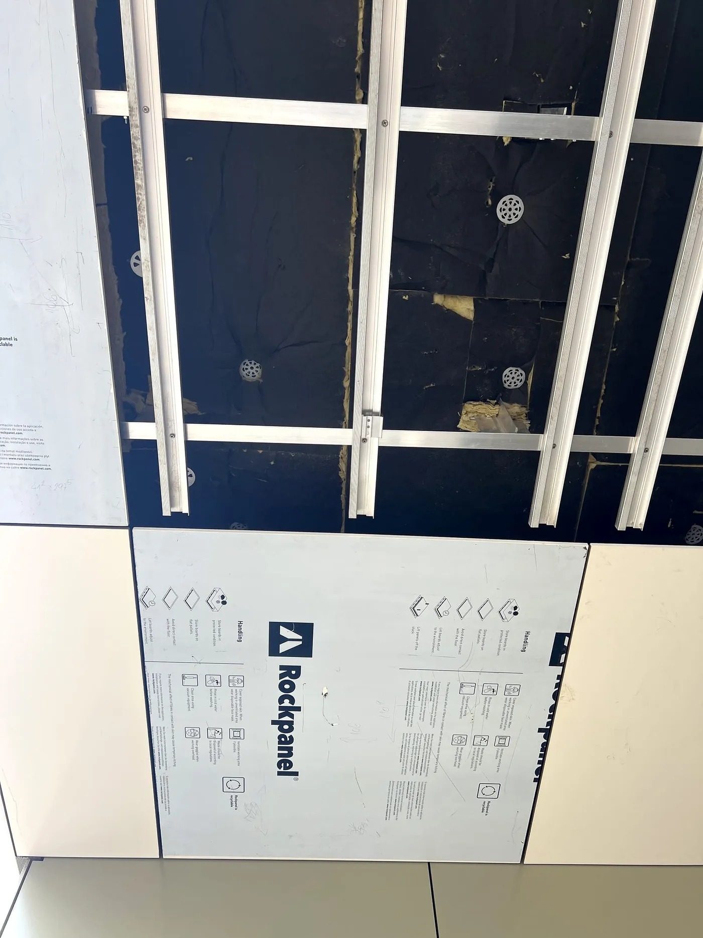Panneau Rockpanel grandes dimensions en cours de pose en plafond suspendu