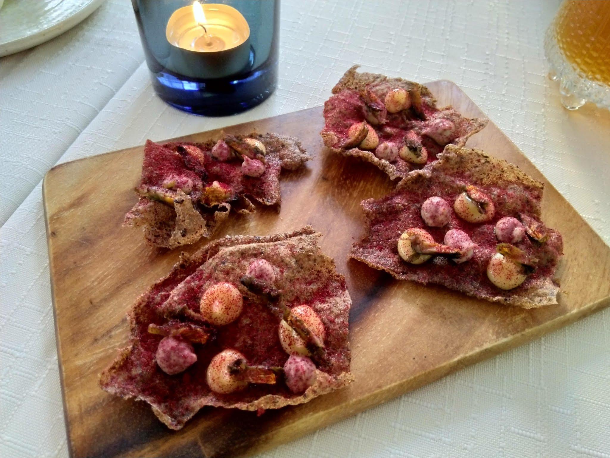 Punajuurijauheella siivilöityjä näkkileipälastuja ja kermapisaroita puualustalla kynttilän vieressä, 05.09.2019