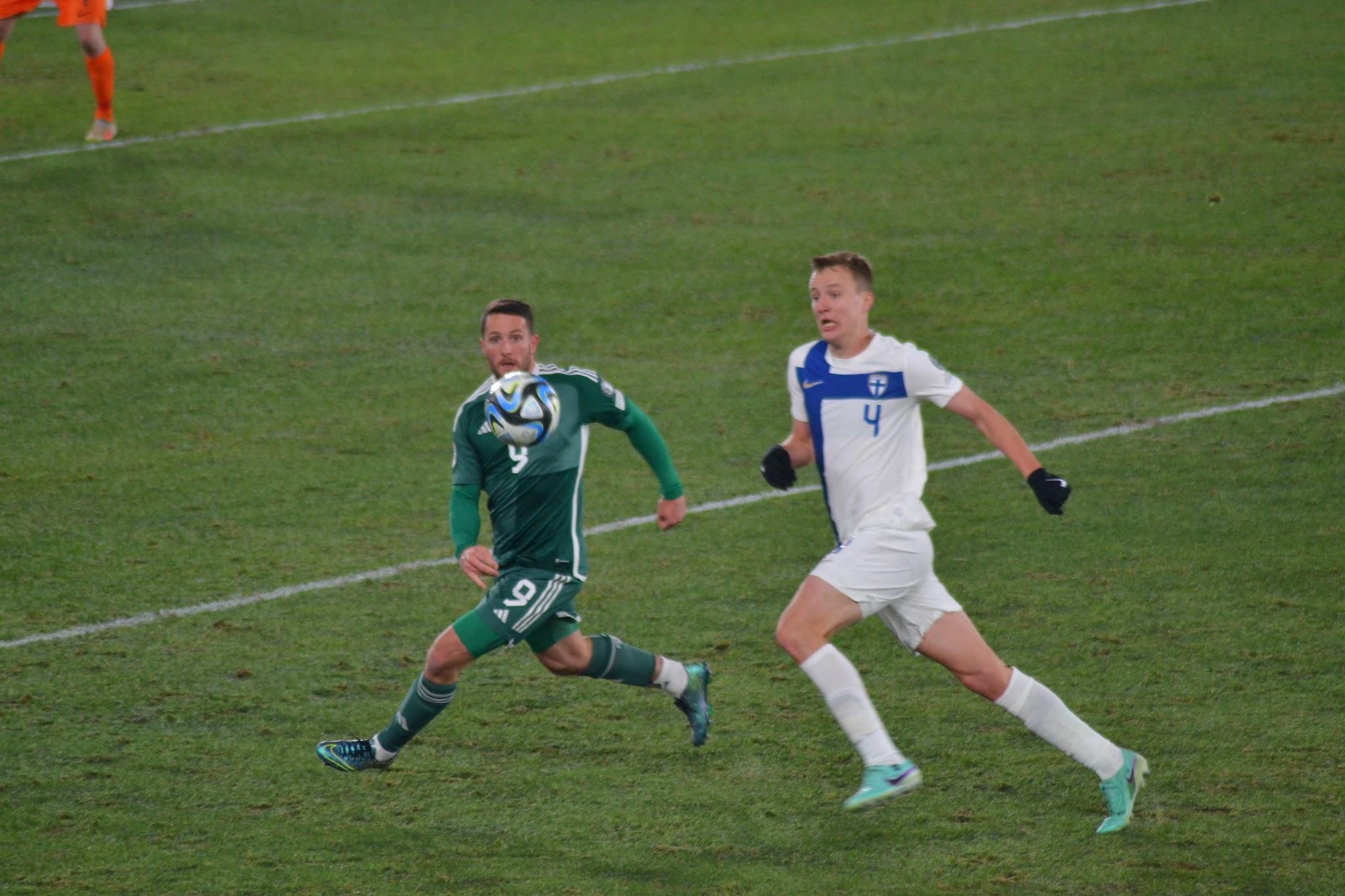 Suomen pelaaja numero 4 ja Pohjois-Irlannin pelaaja numero 9 juoksevat pallon perässä
