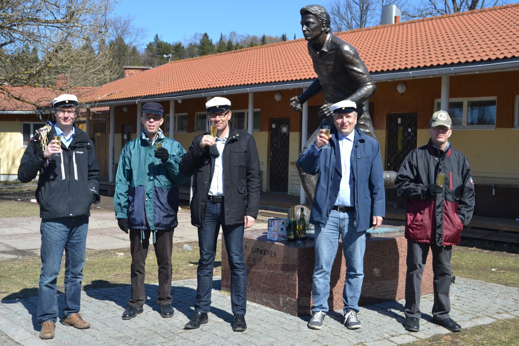 Viisi klubilaista ylioppilaslakeissa nostaa kuohuviinimaljan Jari Litmasen patsaan edessä vappuna