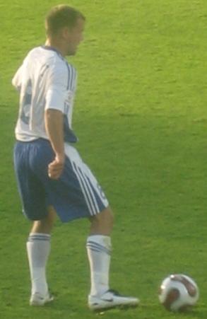Tainio Suomen valko-sinisessä peliasussa pallon vieressä nurmella