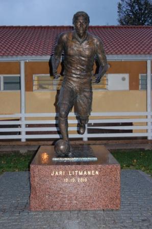 Jari Litmasen pronssipatsas graniittijalustalla hämärässä, jalustassa teksti Jari Litmanen 10.10.2010