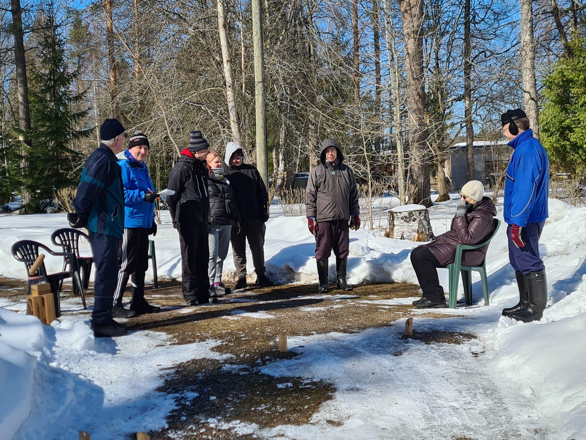 Klubilaiset mölkkykentällä aurinkoisena kevätpäivänä lumihankien keskellä, 01.04.2023