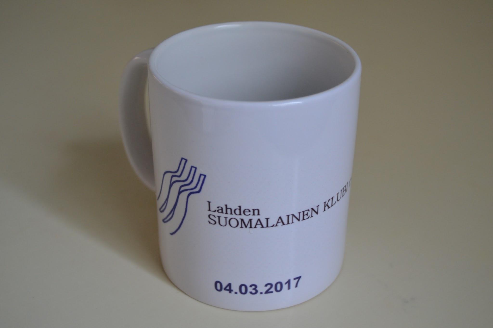Valkoinen muki, jossa Lahden Suomalainen Klubi ry:n logo ja päivämäärä 04.03.2017