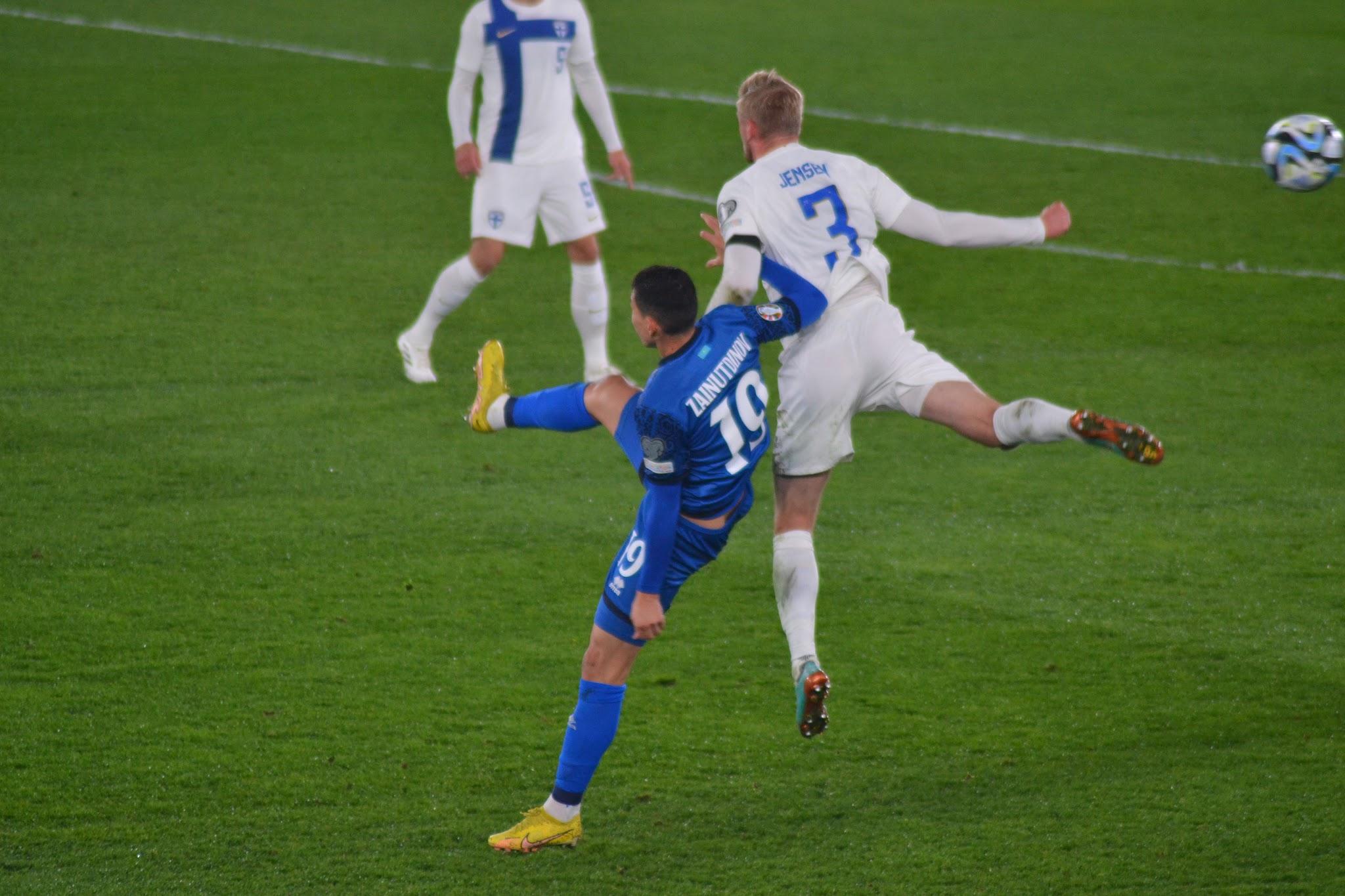 Kazakstanin numero 19 Zainutdinov potkaisee palloa Suomen numero 3 Jensenin hypätessä vieressä