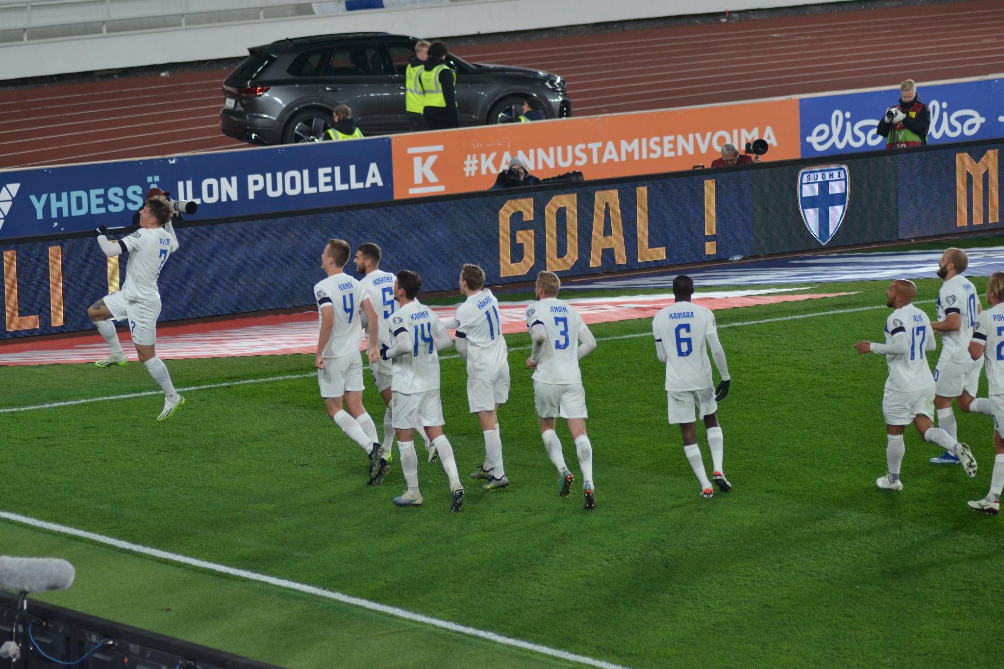 Suomen pelaajat juhlivat maalia kentän laidalla, mainostaululla teksti GOAL! Suomi–Kazakstan-ottelussa