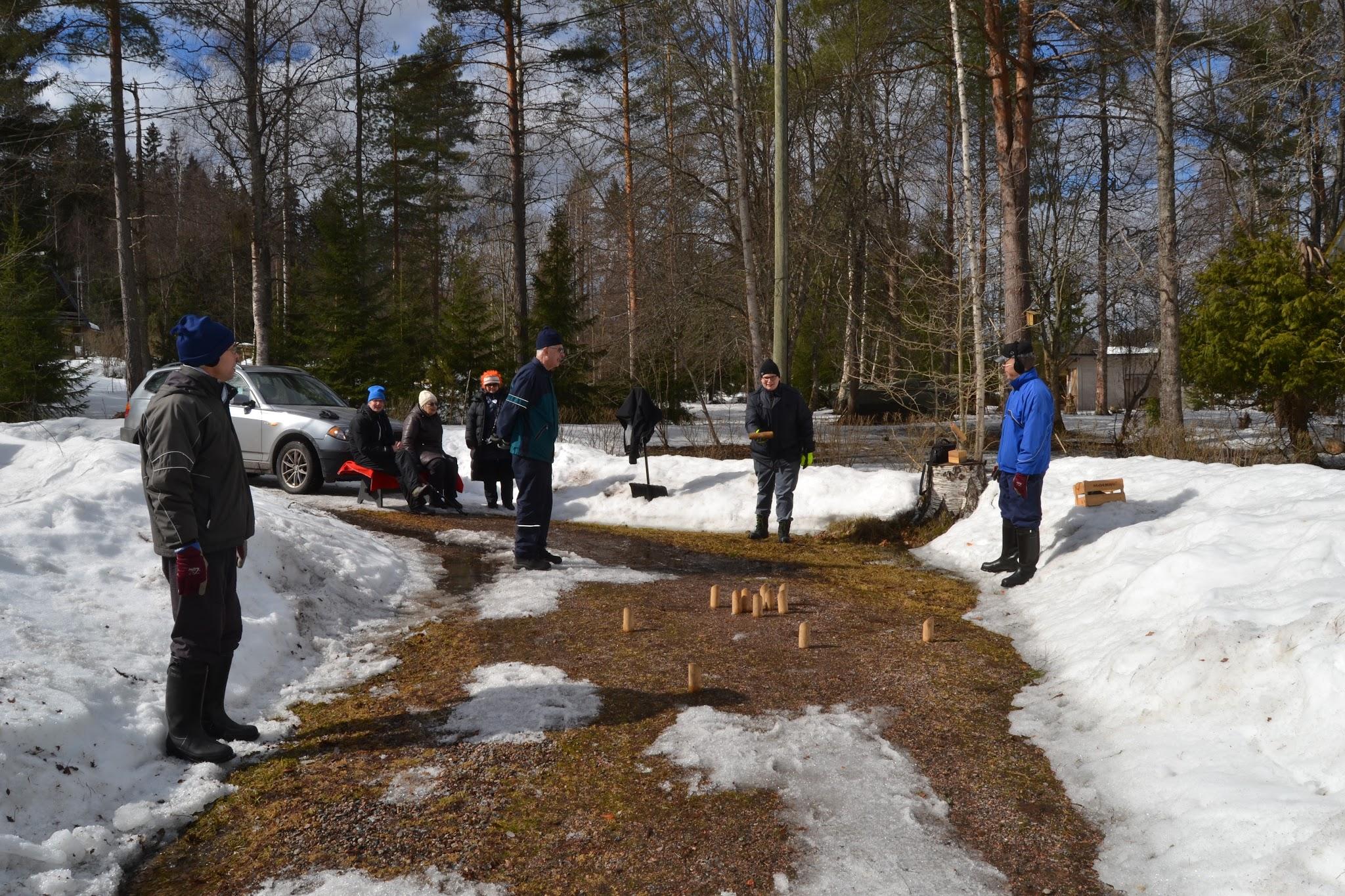 Klubilaisia pelaamassa mölkkyä lumisen pihan sulaneella hiekkatiellä pitkäperjantaina, 15.04.2022