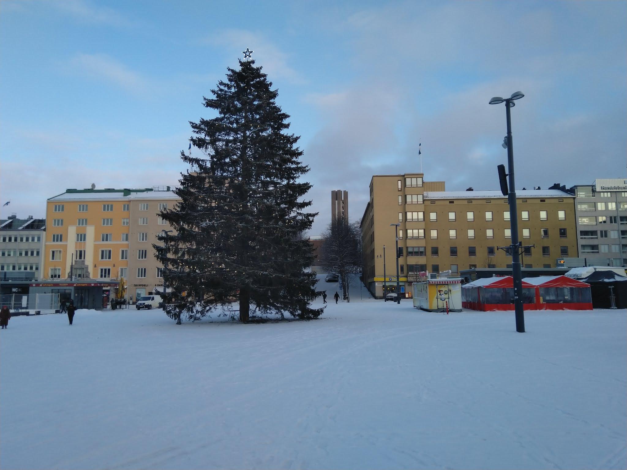 Lahden torin joulukuusi talvisena aamuna, taustalla kerrostaloja ja Suomen lippuja