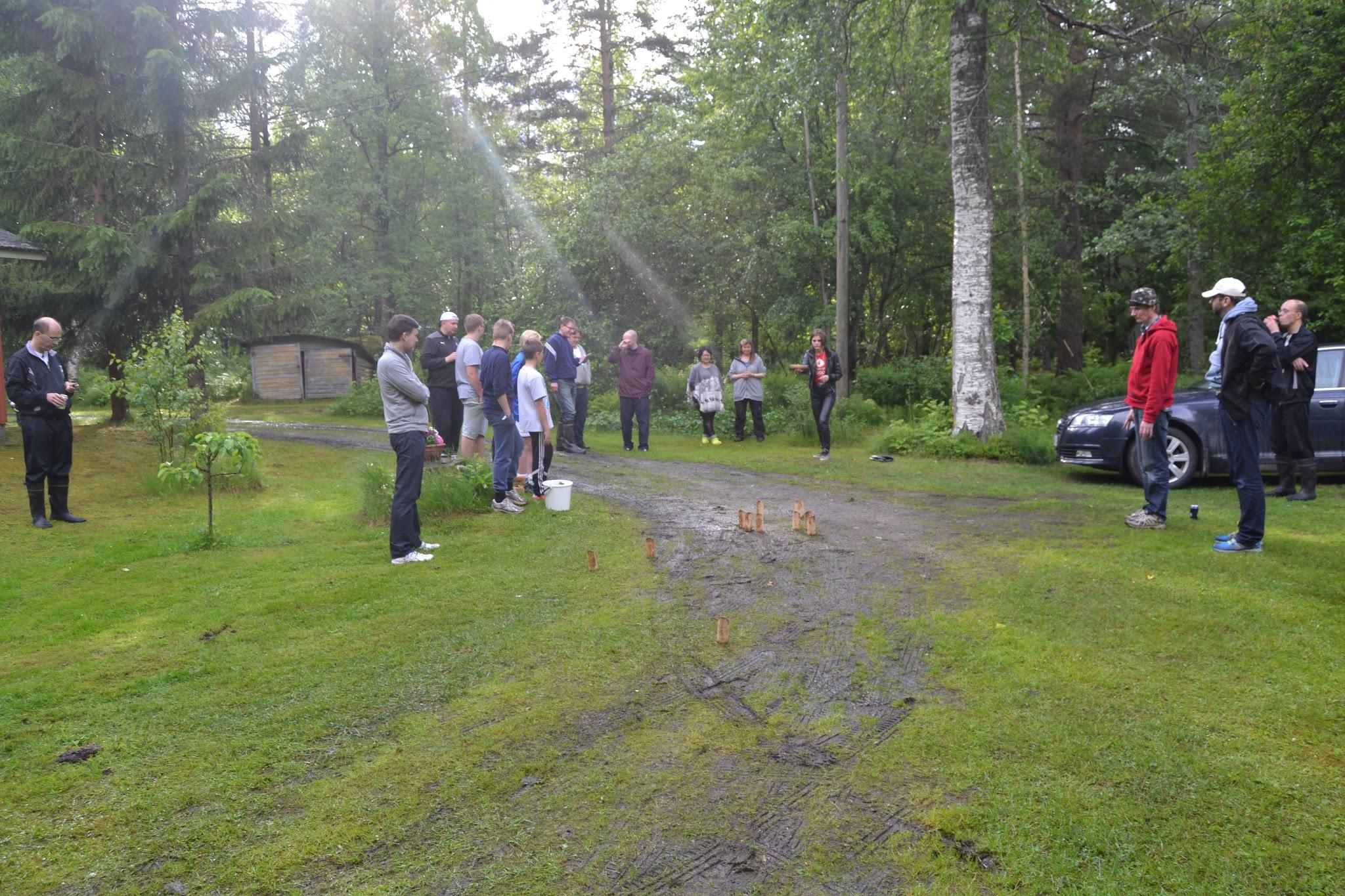Klubilaisia pelaamassa mölkkyä pihanurmella metsän keskellä kesäjuhlassa