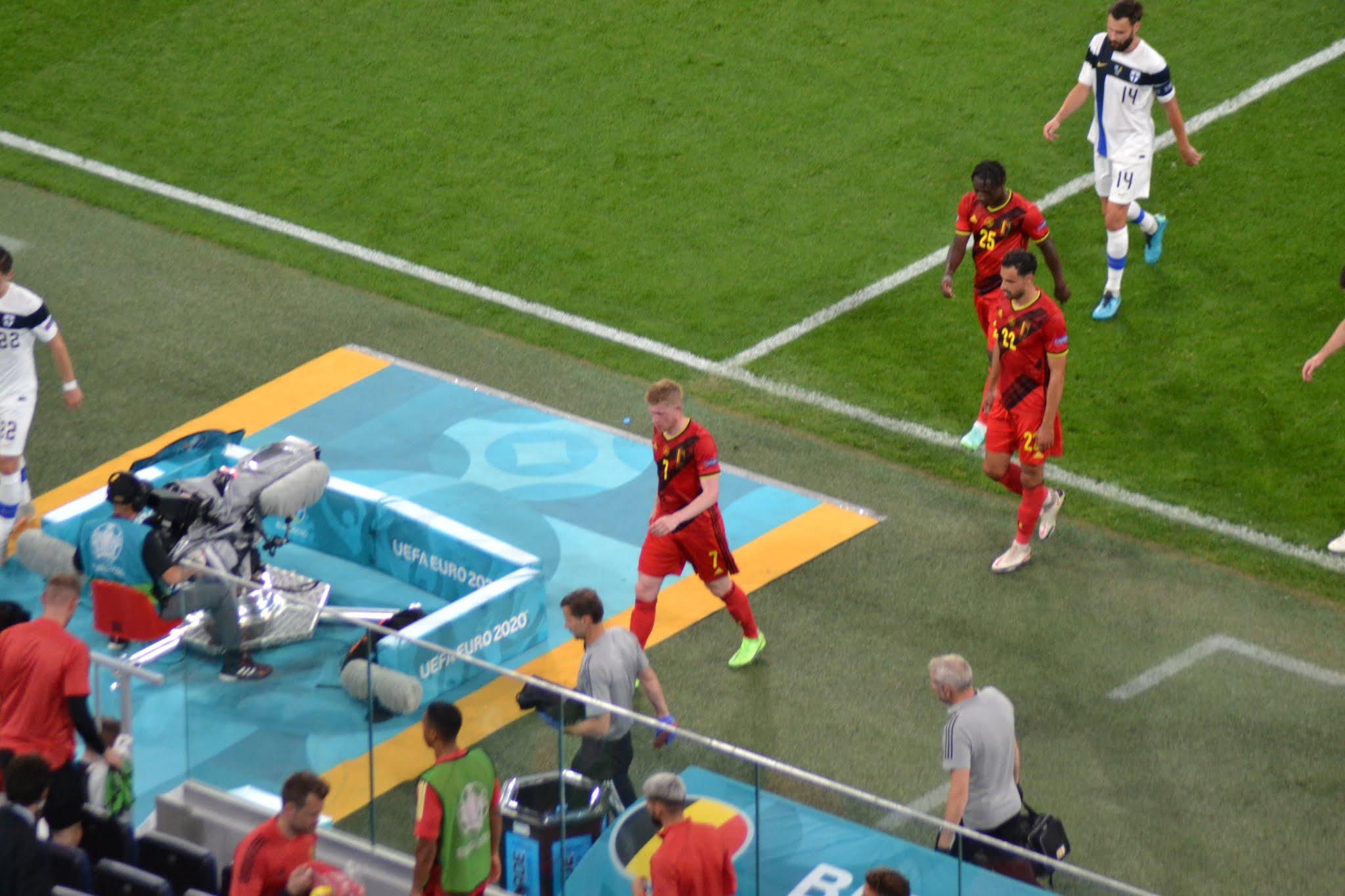 Belgian punapaitaiset pelaajat ja Suomen pelaaja kävelevät sivurajan tuntumassa EURO 2020 -ottelussa