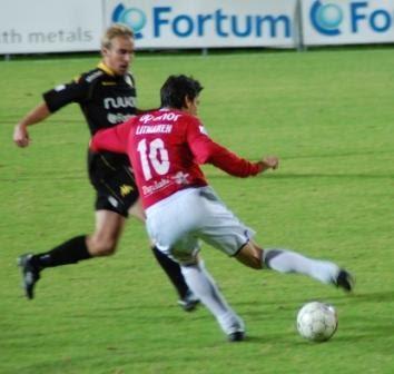 Litmanen punaisessa pelipaidassa numerolla 10 kuljettaa palloa, takana mustakeltaisessa asussa pelaava vastustaja, 04.10.2010
