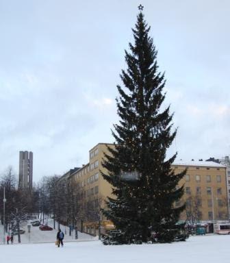 Tähtilatvainen joulukuusi lumisella torilla, taustalla kerrostaloja ja korkea betonitorni, 24.12.2009