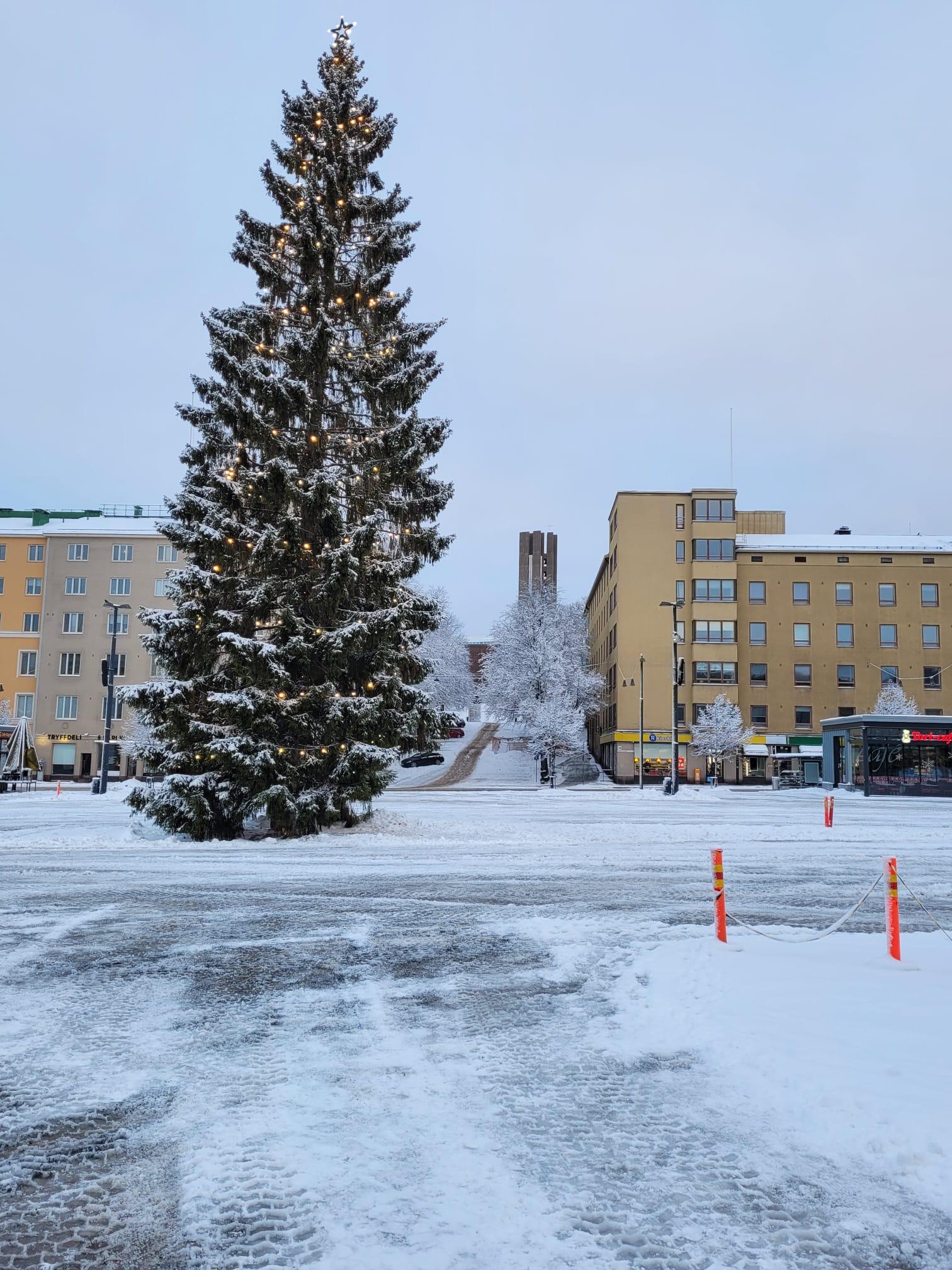 Valoin koristeltu joulukuusi lumisella Lahden torilla, taustalla kerrostaloja, 24.12.2022