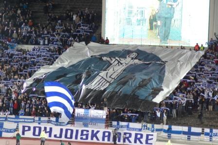 Suomen kannattajat nostavat jättitifon Olympiastadionin katsomossa Pohjoiskaarre-banderollin yllä, 07.09.2012