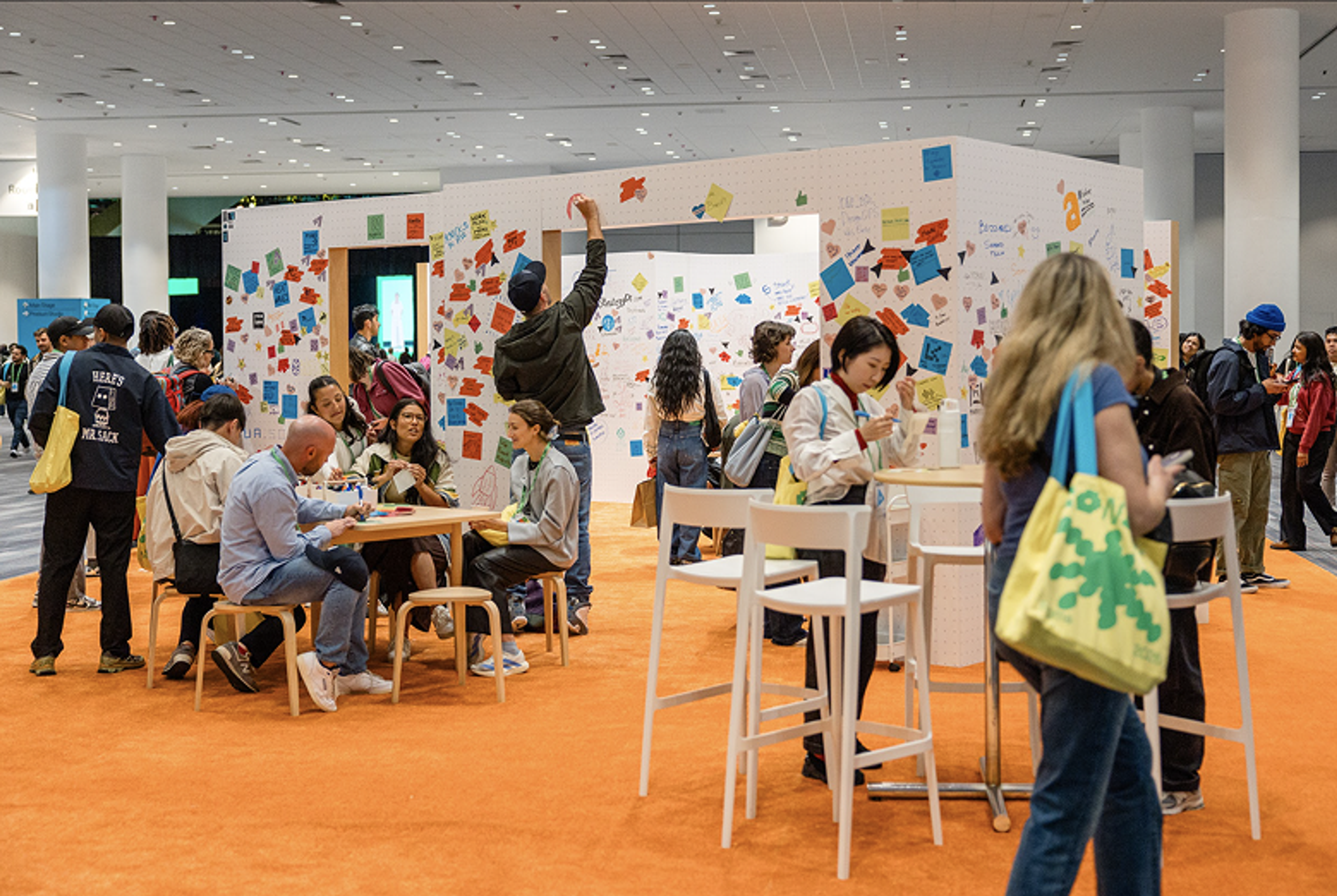 Config attendees adding notes and visuals to creative wall at Config