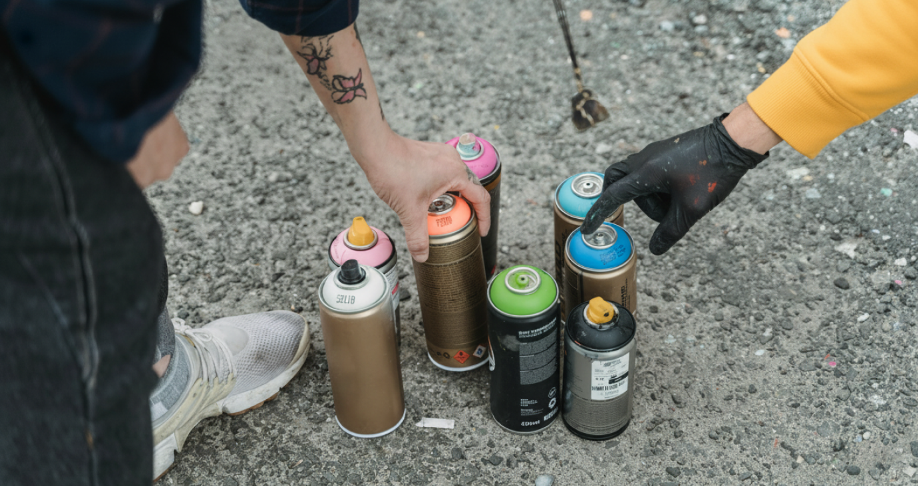 Spray paint cans on concrete being grabbed by people for graffiti