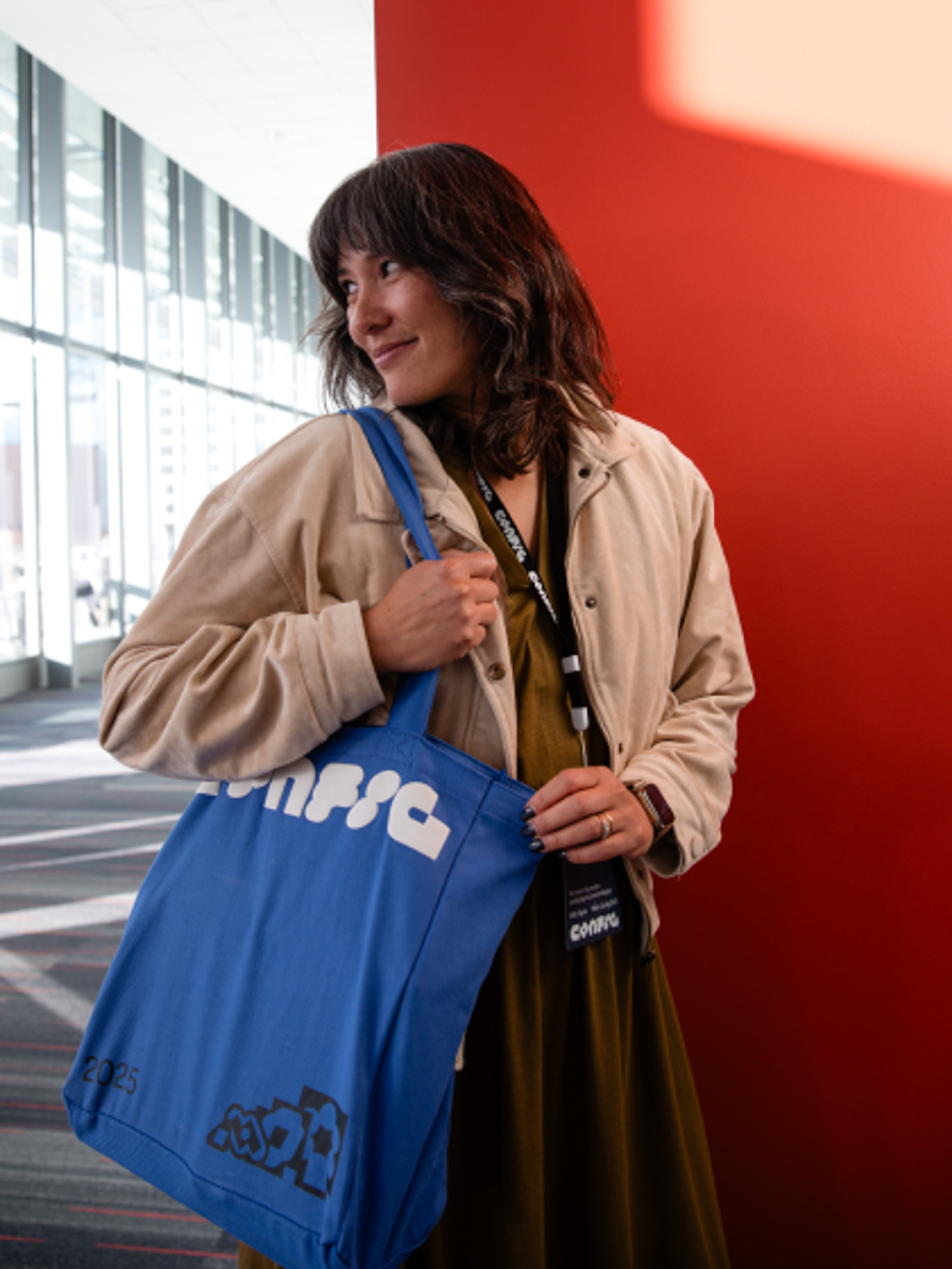 Config attendee smiling outside while holding a Config tote bag