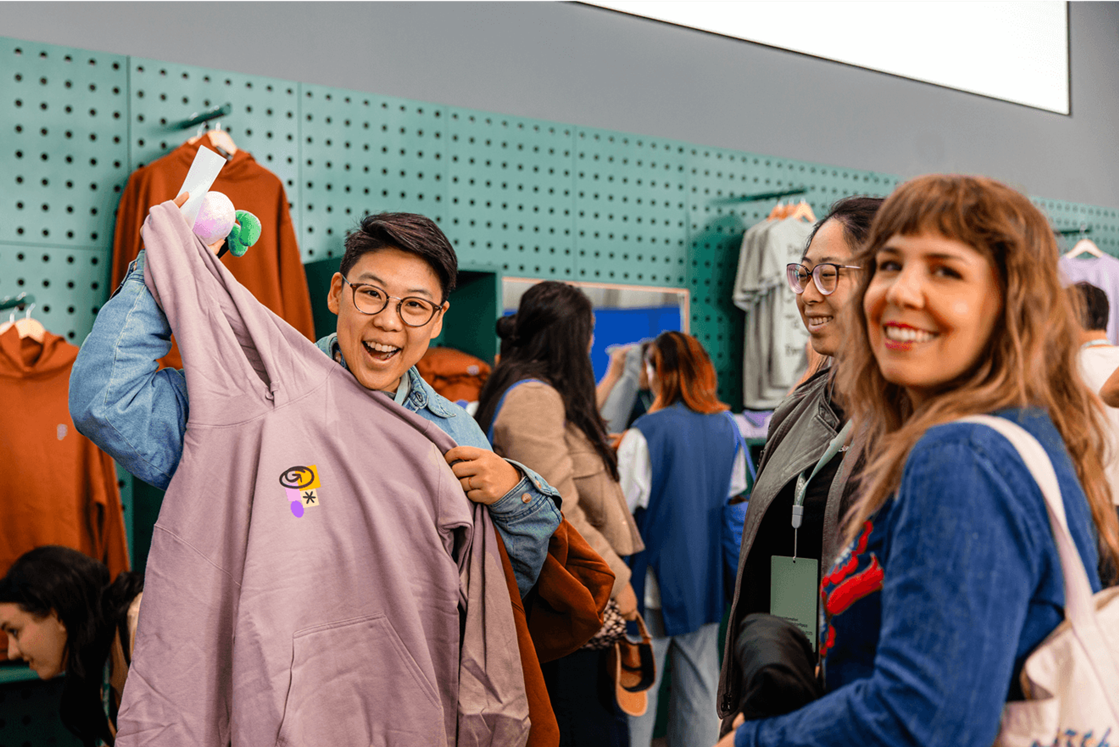 Attendee holding up a lavender hoodie while shopping at the Config merchandise store.
