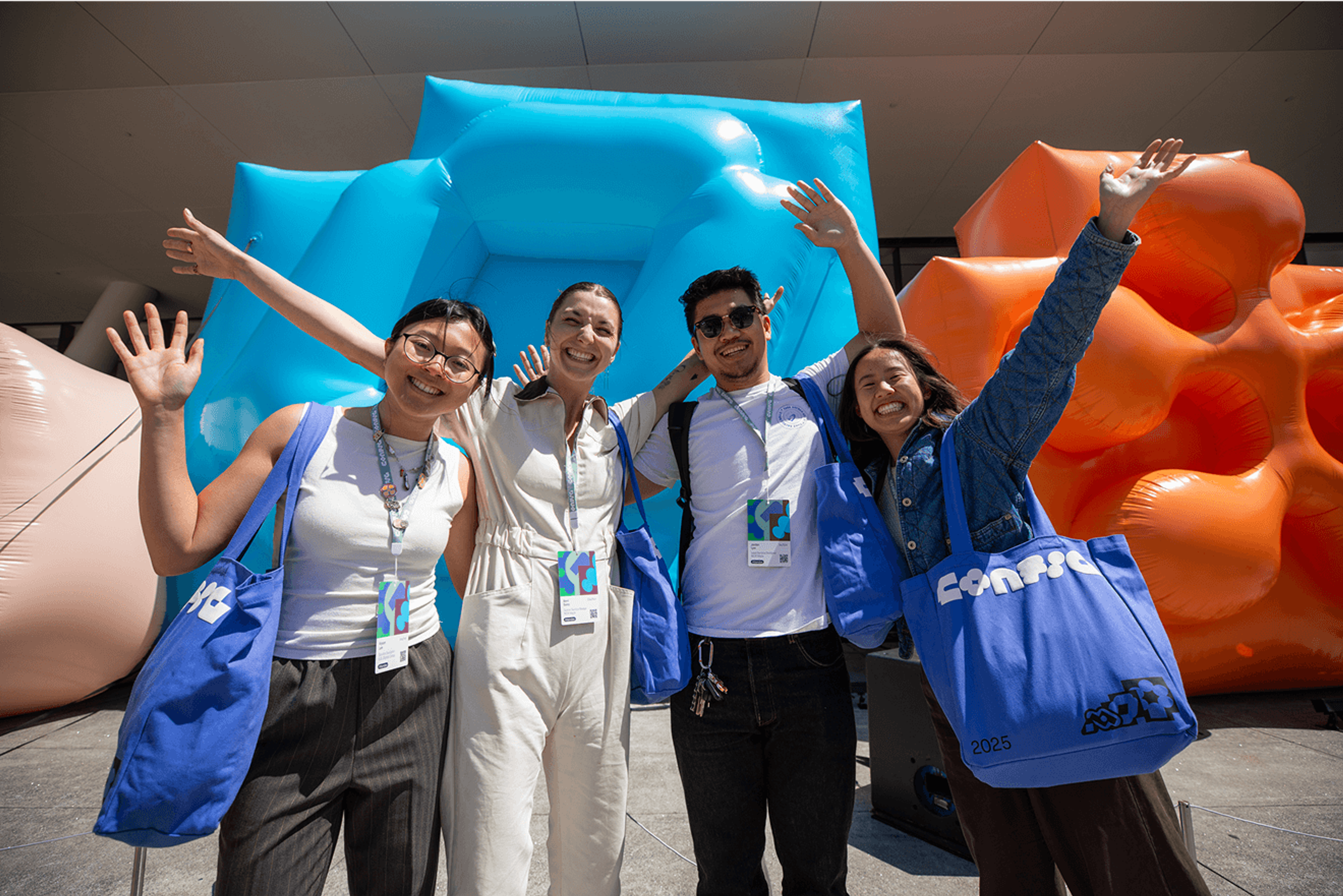 Four smiling attendees posing in front of colorful inflatable shapes with Figma tote bags.