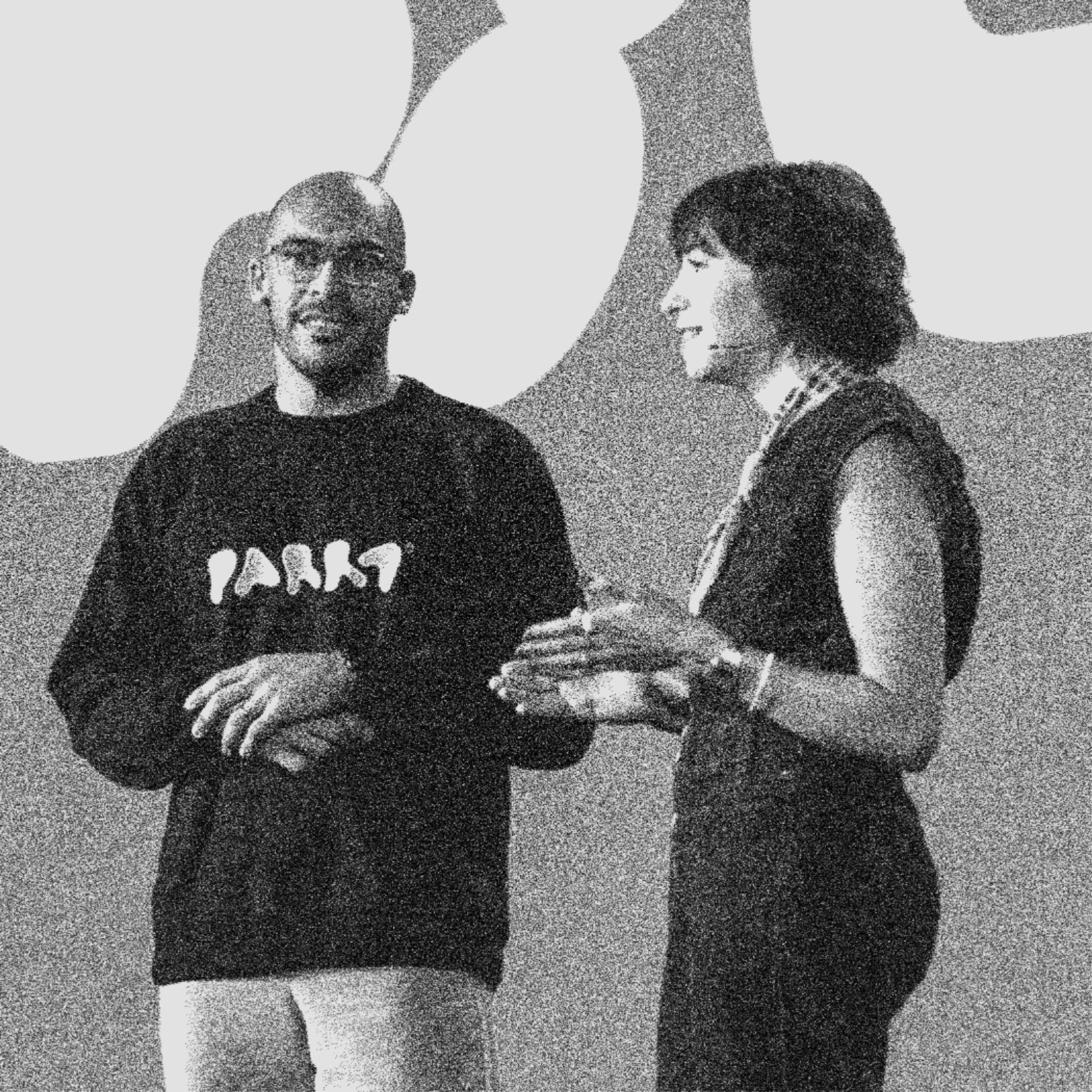 Two speakers on stage at Figma Config 2025, one wearing a black sweatshirt and the other in a denim jumpsuit with a red scarf, engaged in conversation.