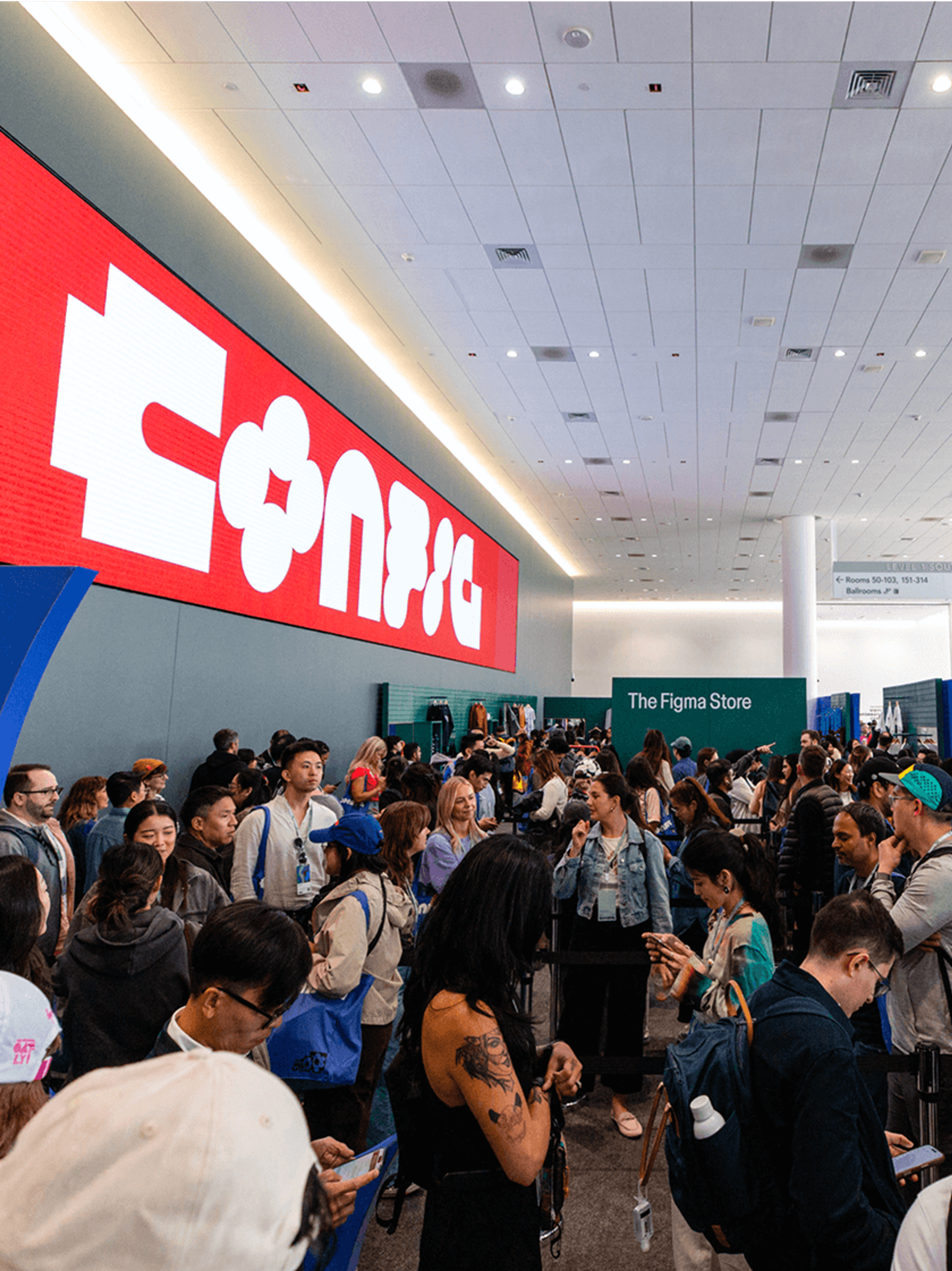 Attendees lined up inside the venue near The Figma Store with a large digital sign above.