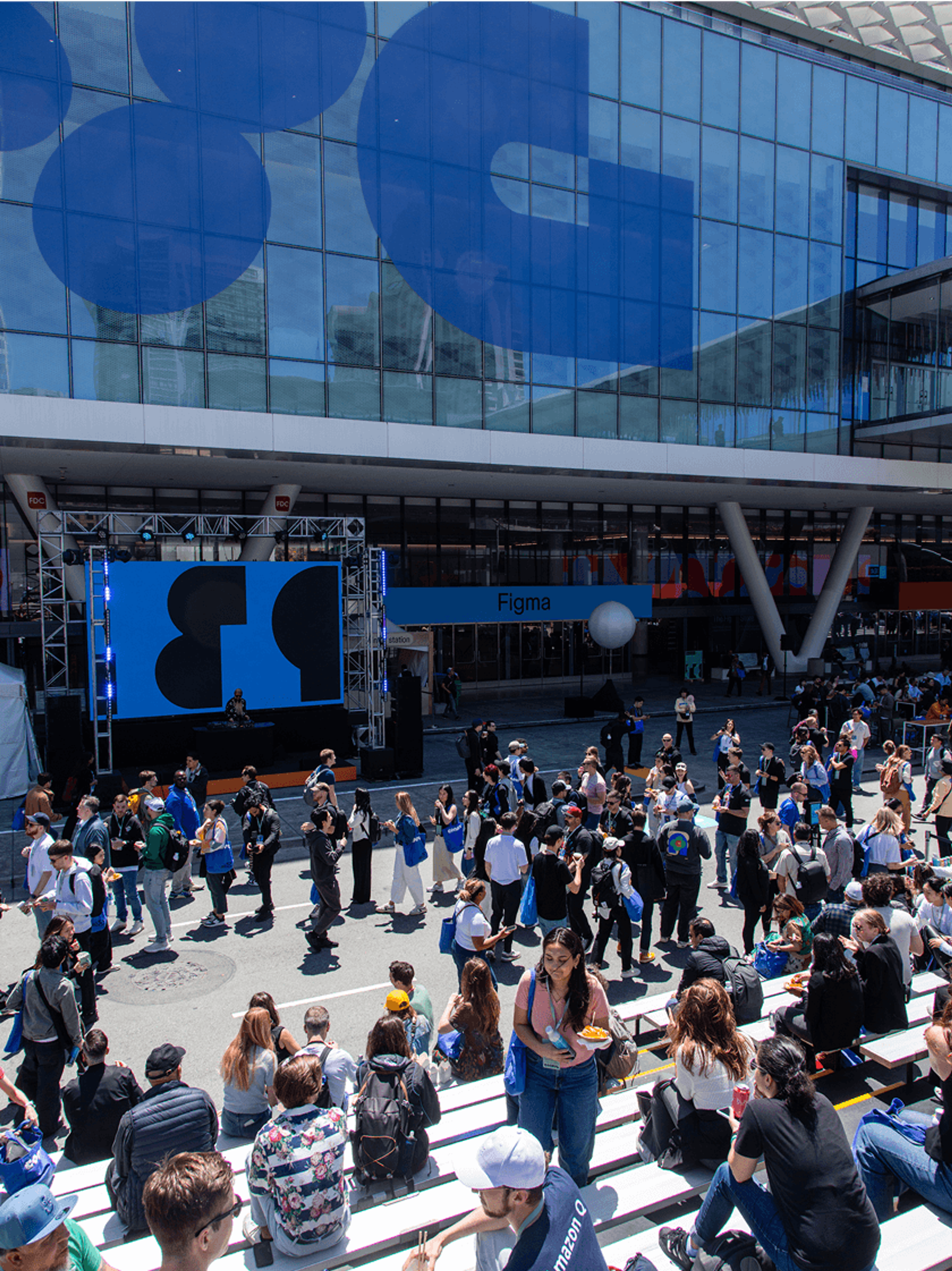 Large crowd gathered outside the Figma Config venue in front of a stage with a big logo on the building windows.