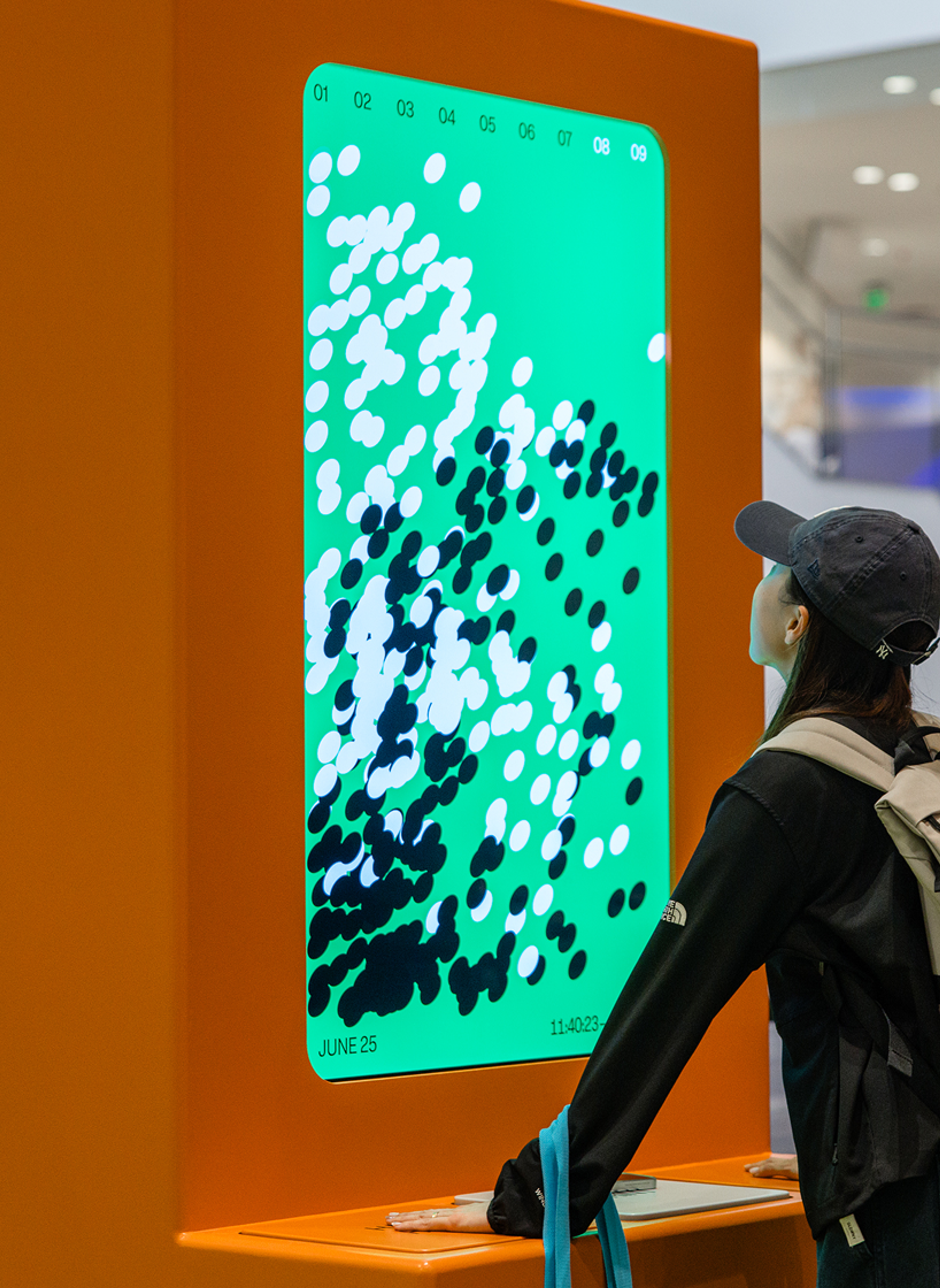 An attendee looking at a screen of abstract green, white, and black dots