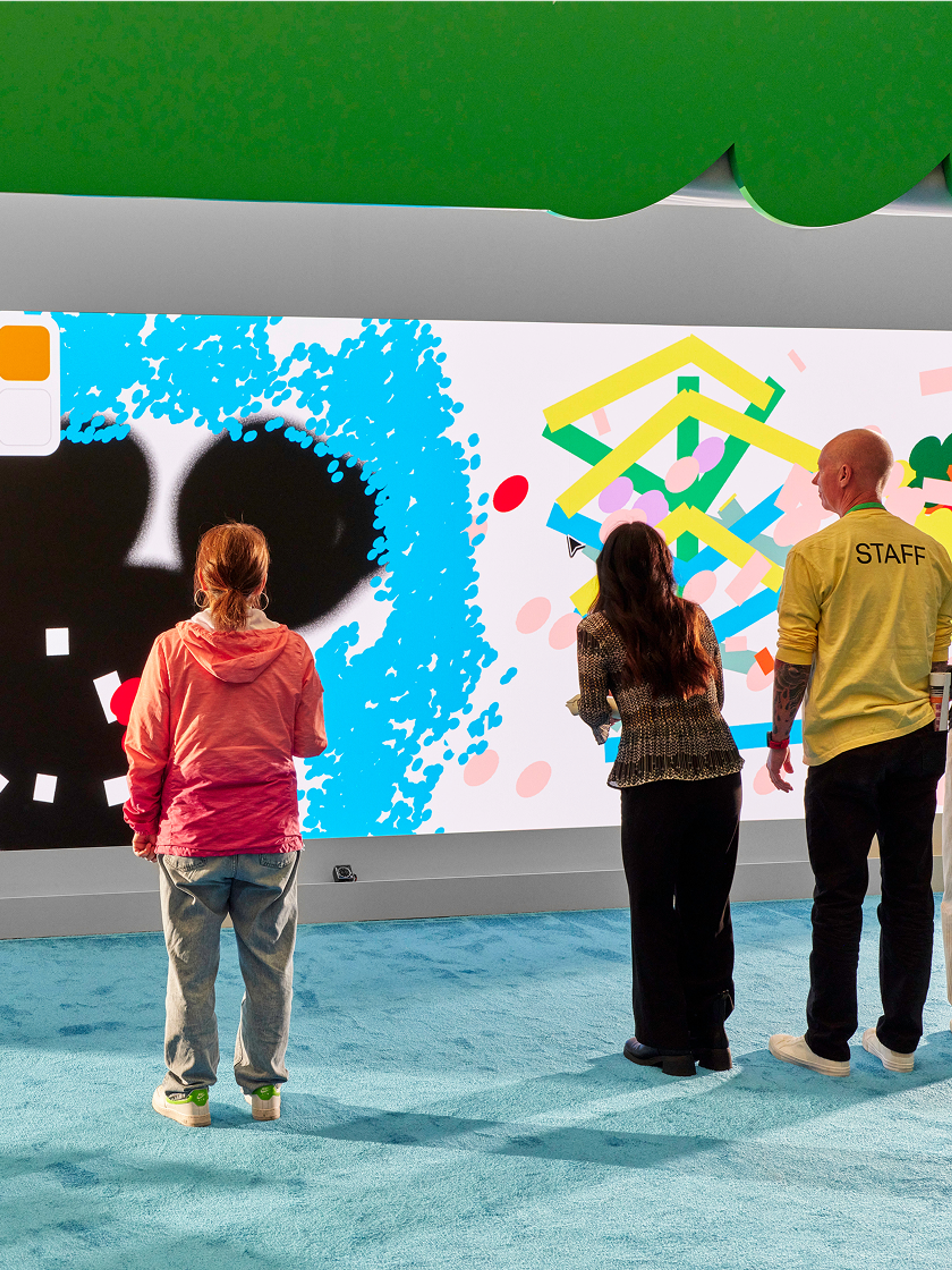 Attendees playing with color virtual art on a large wall