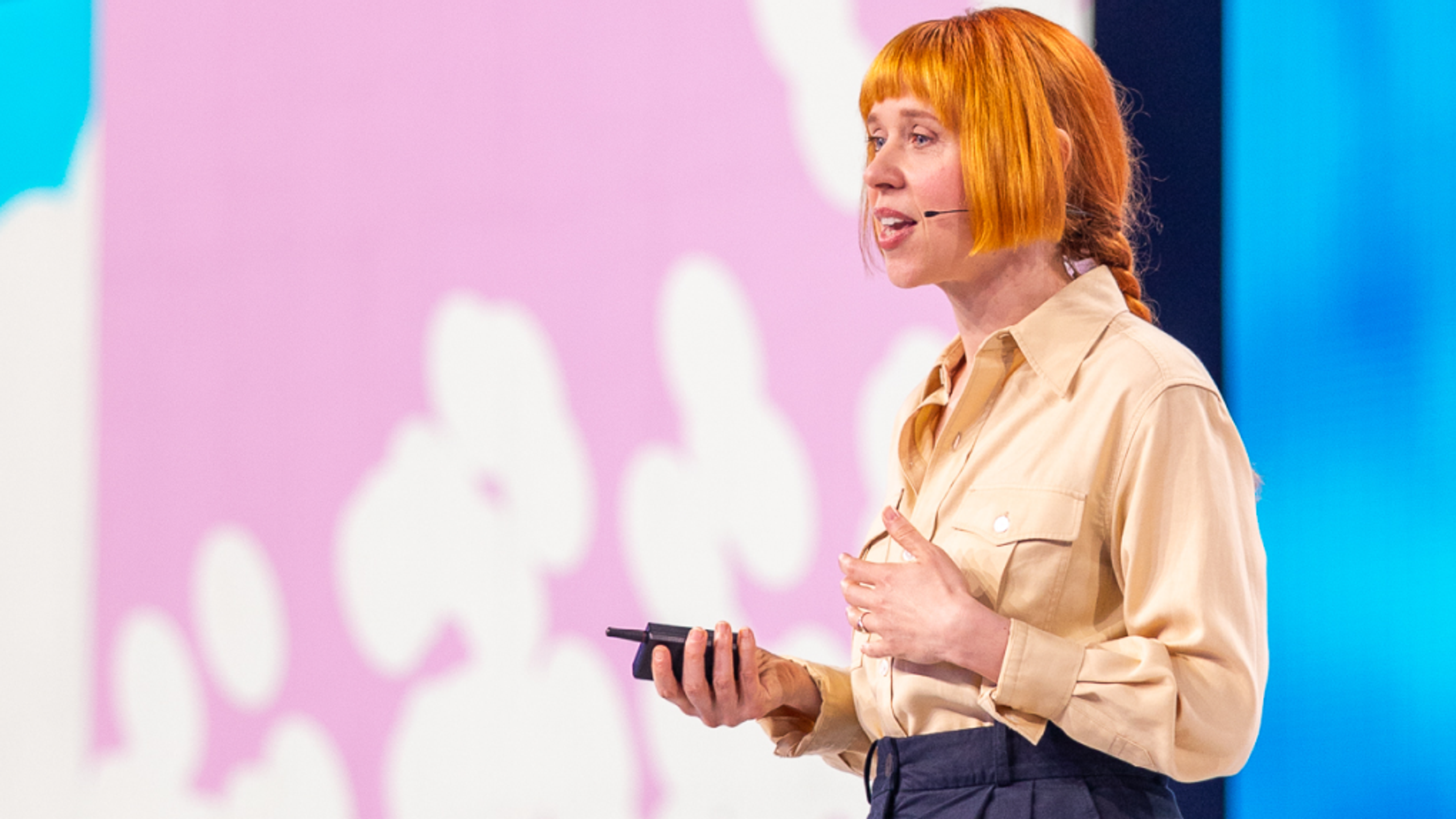 Holly speaking on stage with pink and blue background