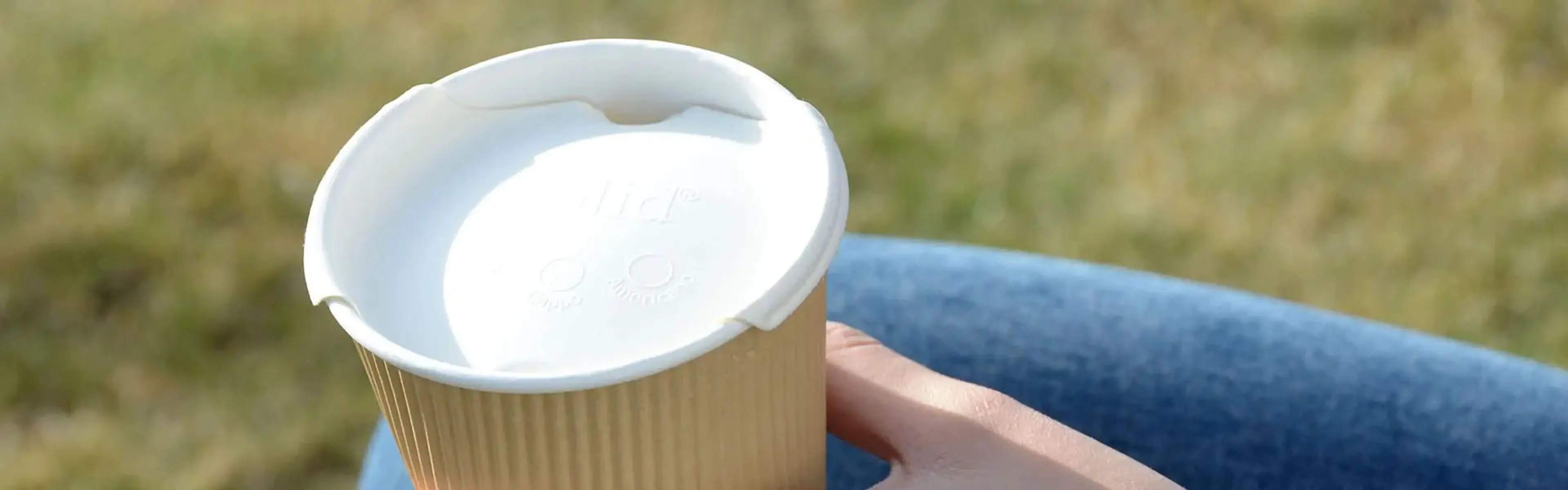 Hånd som holder kopp med Liplid-lokk