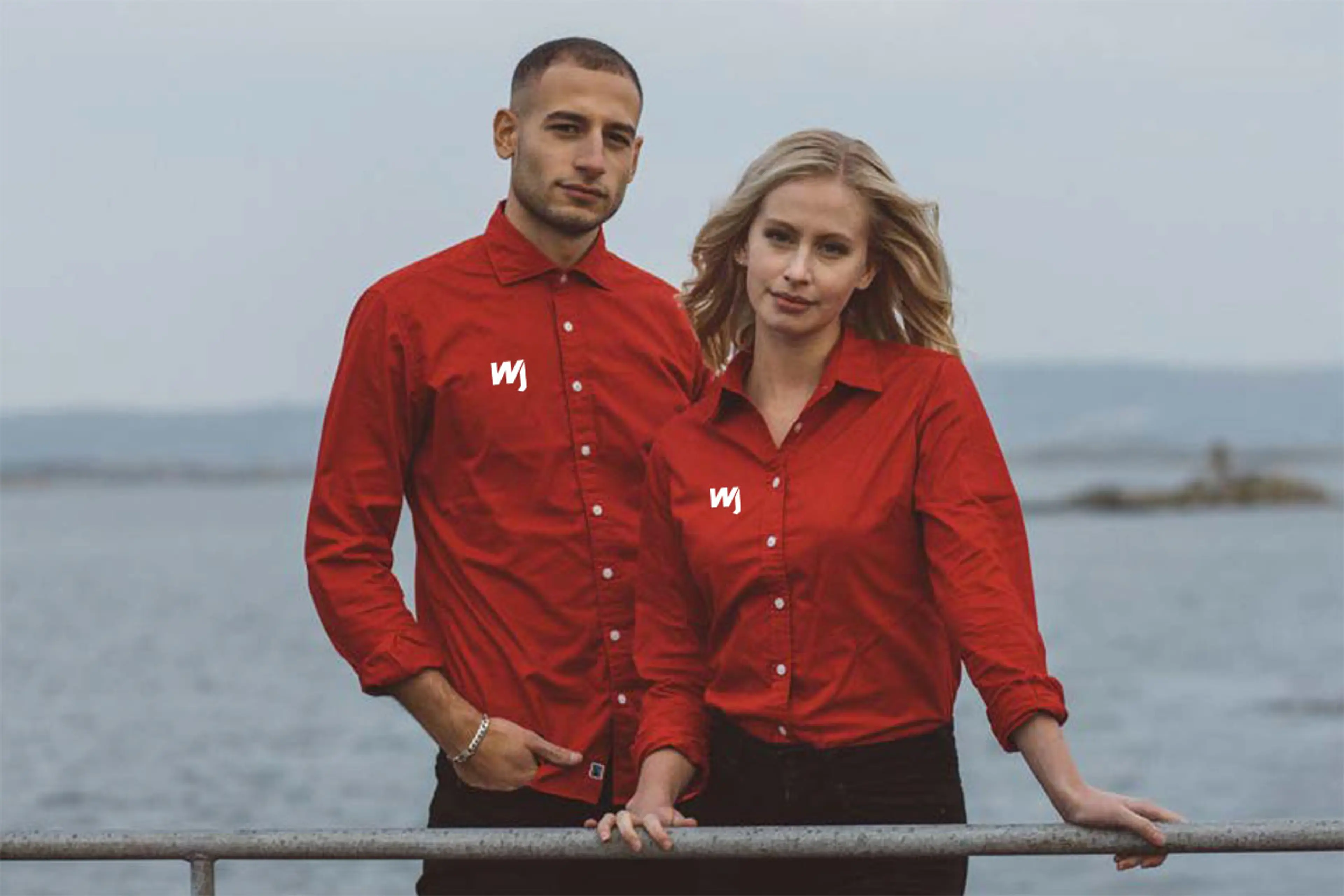Mann og dame ved sjøen med firmaprofilerte skjorter