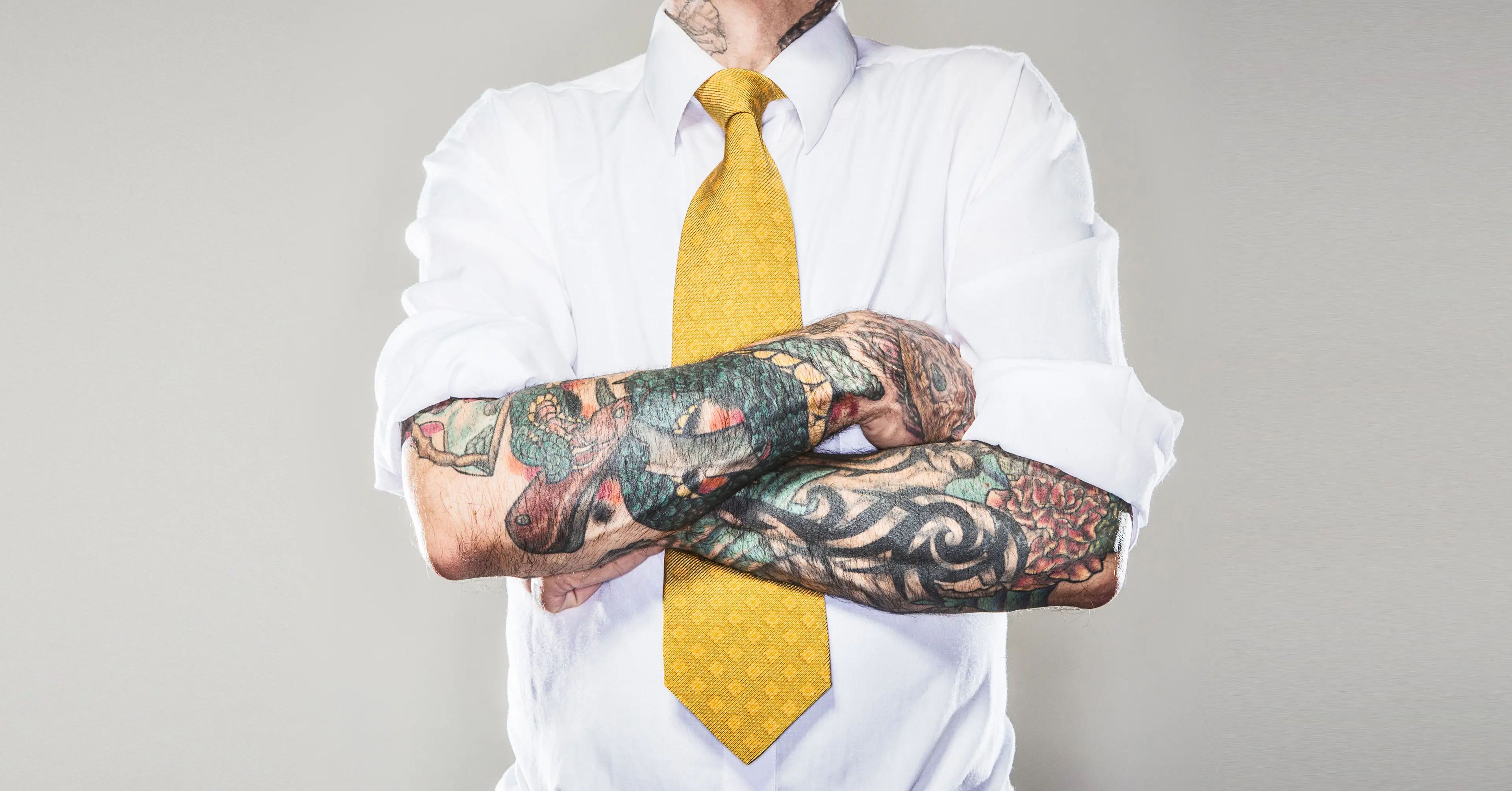 Mann med tatoveringer i skjorte og slips