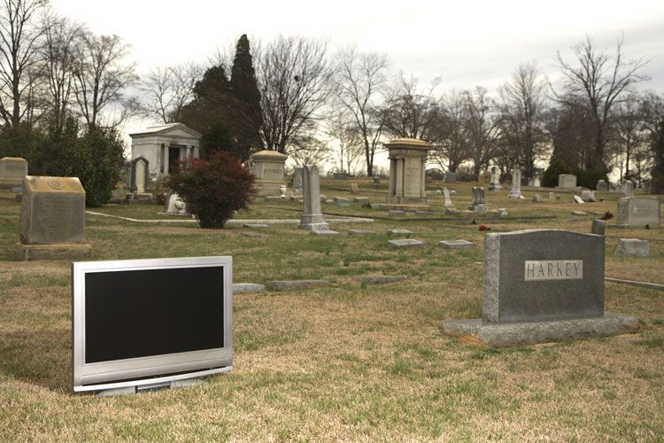 flatscreen next to a headstone in a cemetery