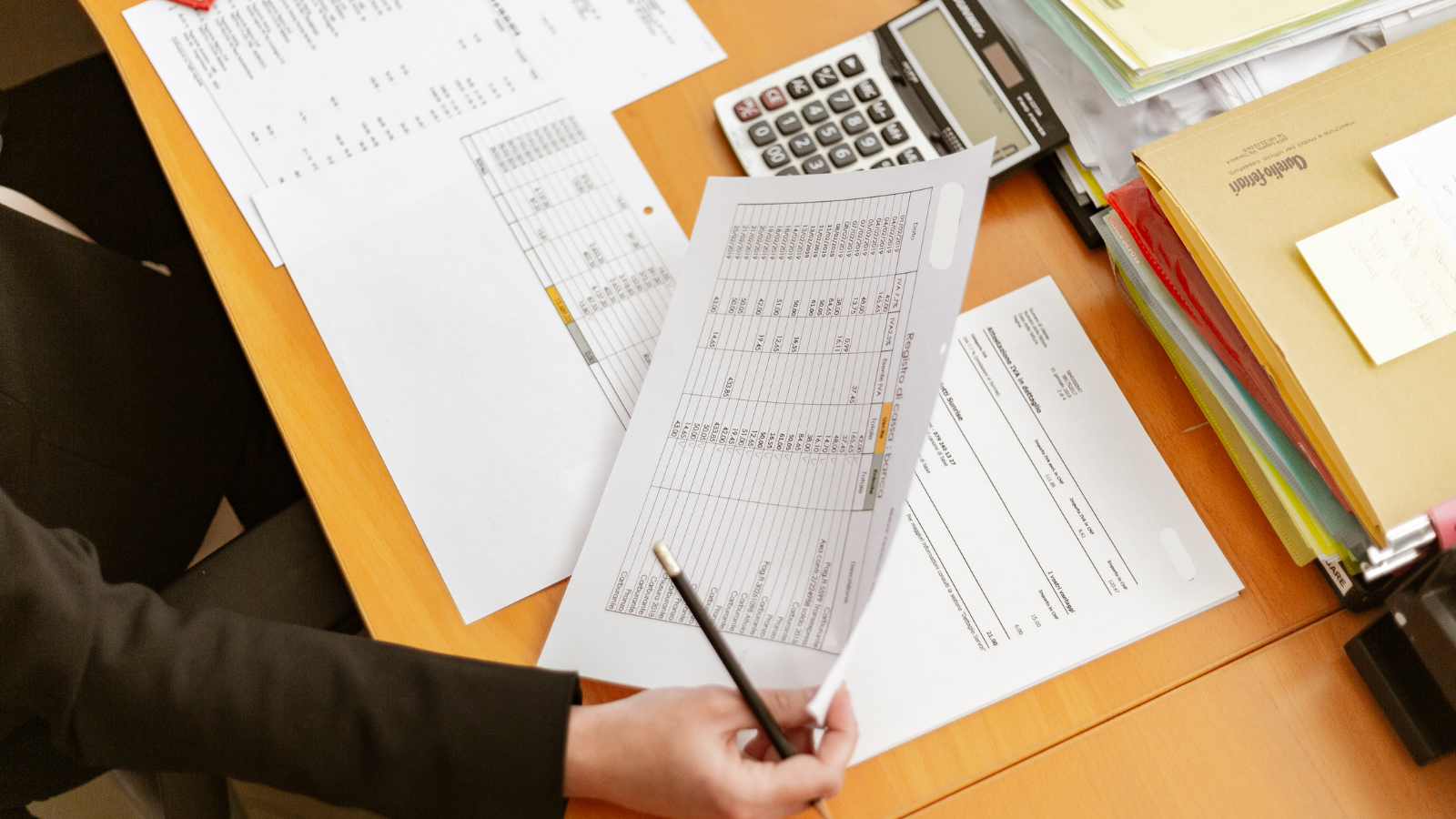 Business owner reviewing documents with a calculator on the table.