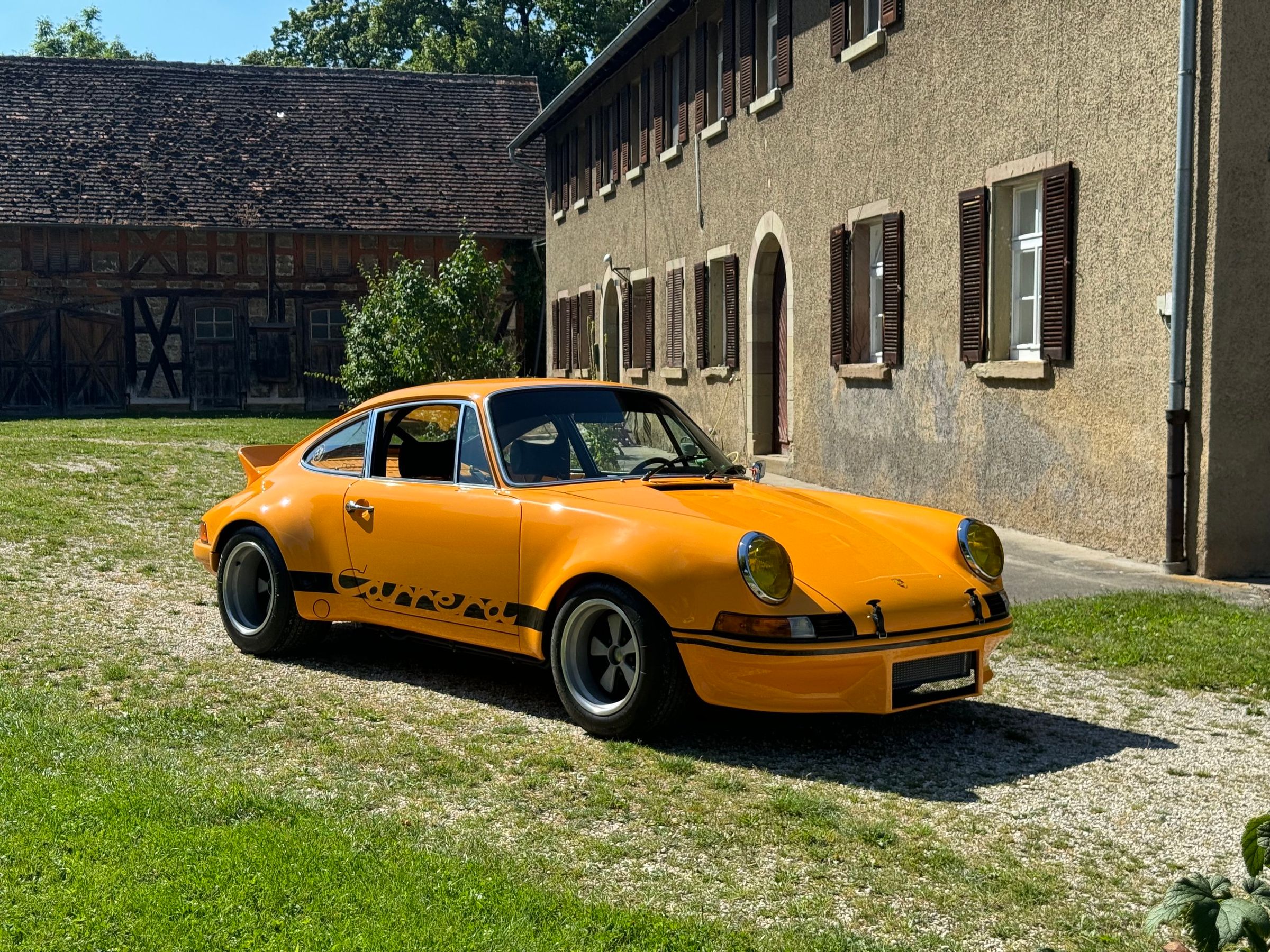 Yellow classic Porsche 911 outside a country building