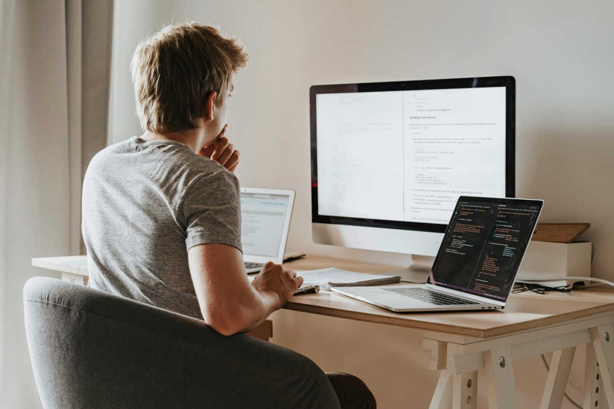 Man sitting in front of three computer screens
