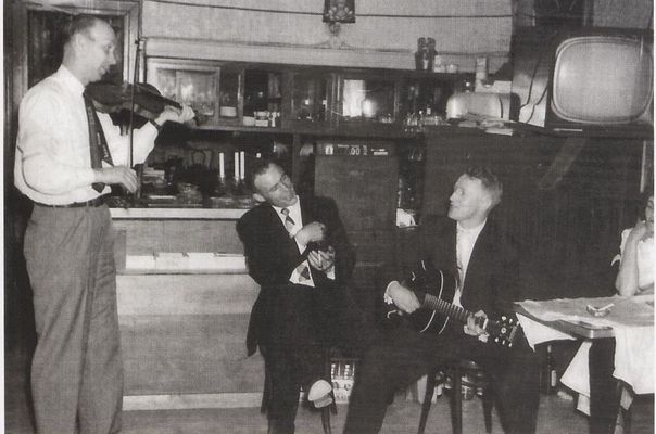 Julius Kristiansen underholder med fiolinspill i kafeen Fredheim bildet hentet Karmøybuer i New York og New Jersey : emigranter, remigranter og pendlere fra Karmøy