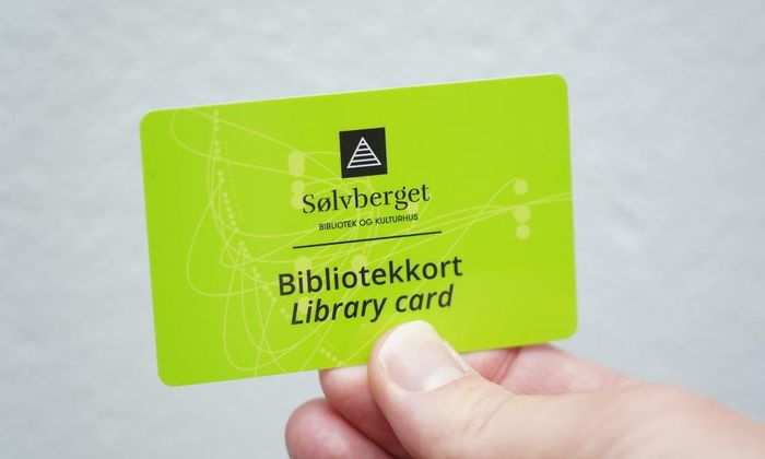 En hånd holder et grønt Sølvberget biblotekkort