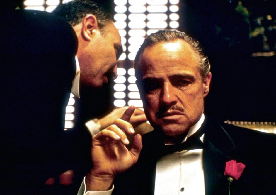 En mann hvisker i øret til en annen. Foto hentet fra filmen The Godfather fra 1972..