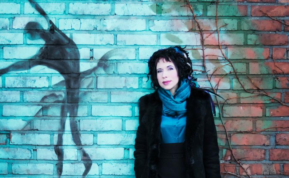 Sofi Oksanen standing in front of a brick wall