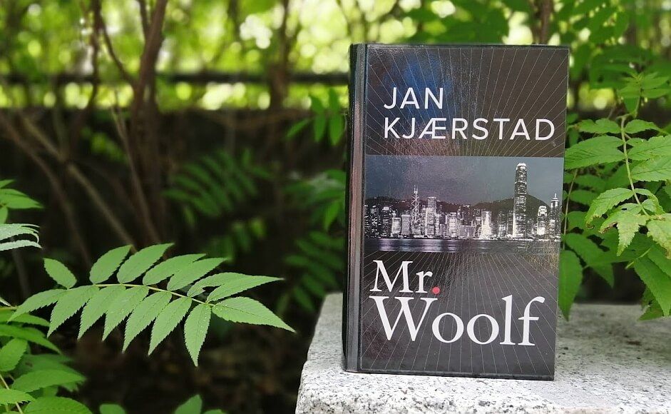 Boka Mr. Woolf av Jan Kjærstad stående på en stein i skogen