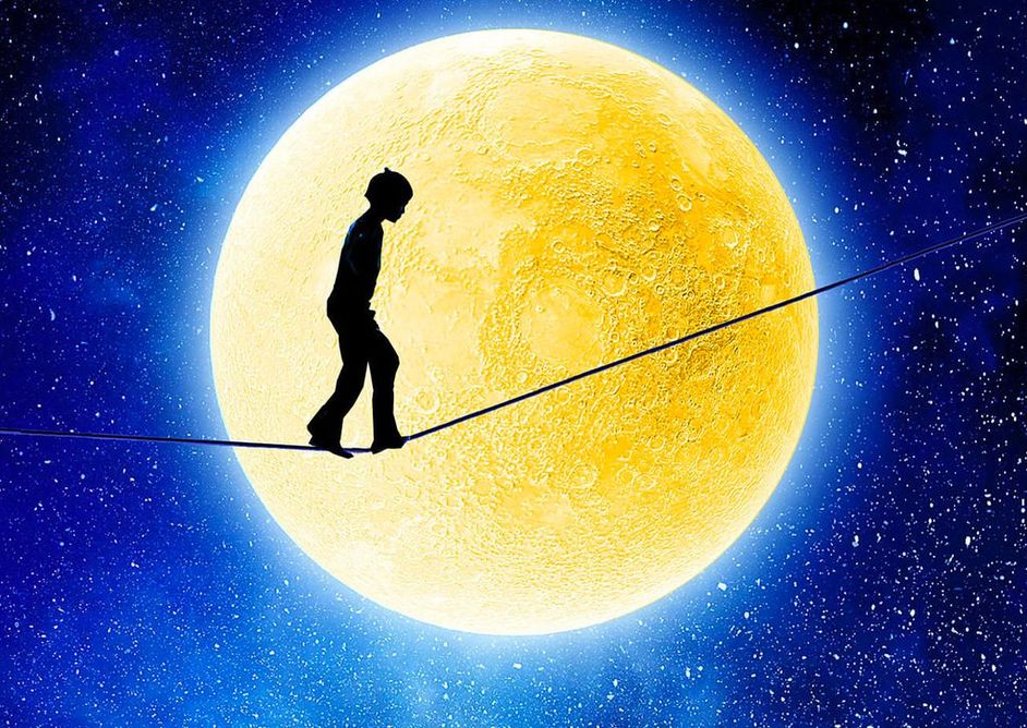 Barn som balanserer på en line i lyset fra en stor gul måne