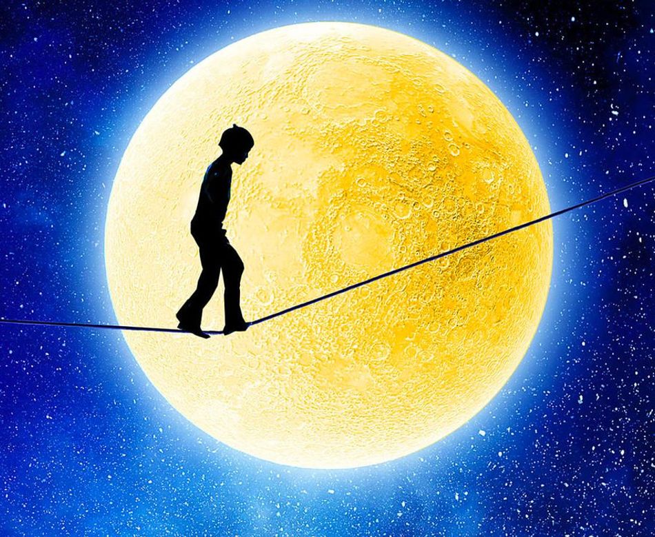 Barn som balanserer på en line i lyset fra en stor gul måne