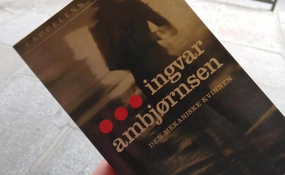 Hånd som holder boken Den mekaniske kvinnen i en gate