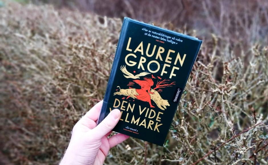 Boka Den vide villmark av Lauren Groff holdt foran en hekk