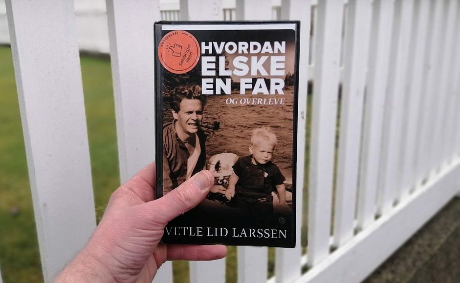Hvordan elske en far og overleve av Vetle Lid Larssen holdt foran et gjerde