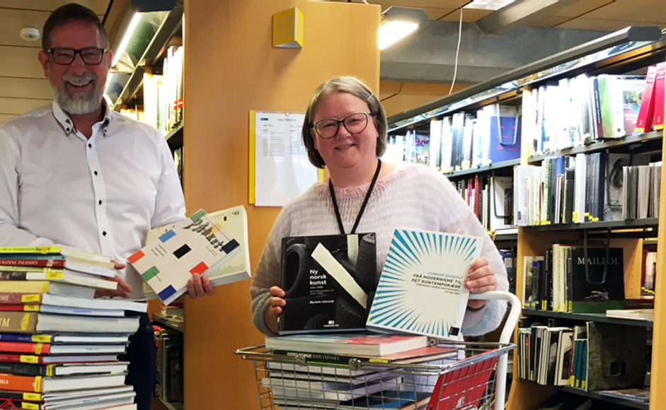 To kunstnere viser frem kunstbøker i biblioteket