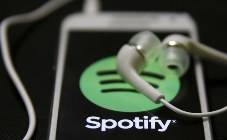 Mobiltelefon med Spotify øreplugger liggende oppå