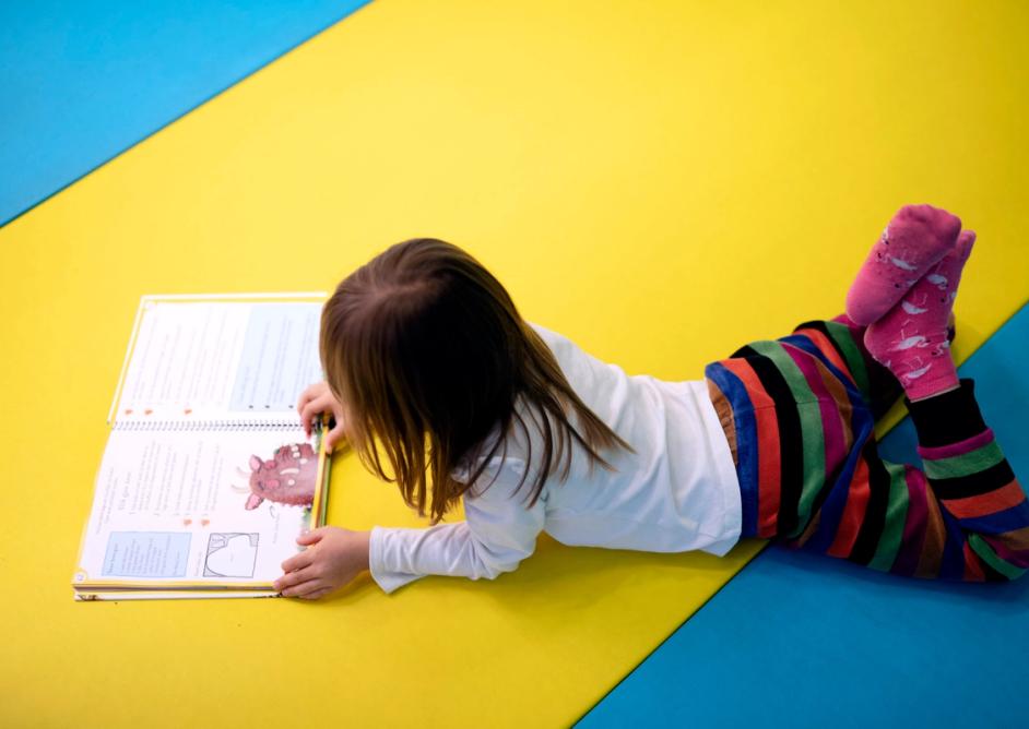 Jente ligger på gulvet og leser en bok