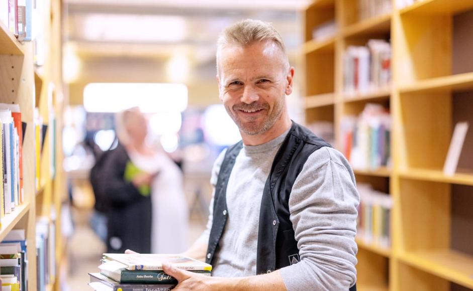 Pål Fjelde holder en bunke med bøker i hendene